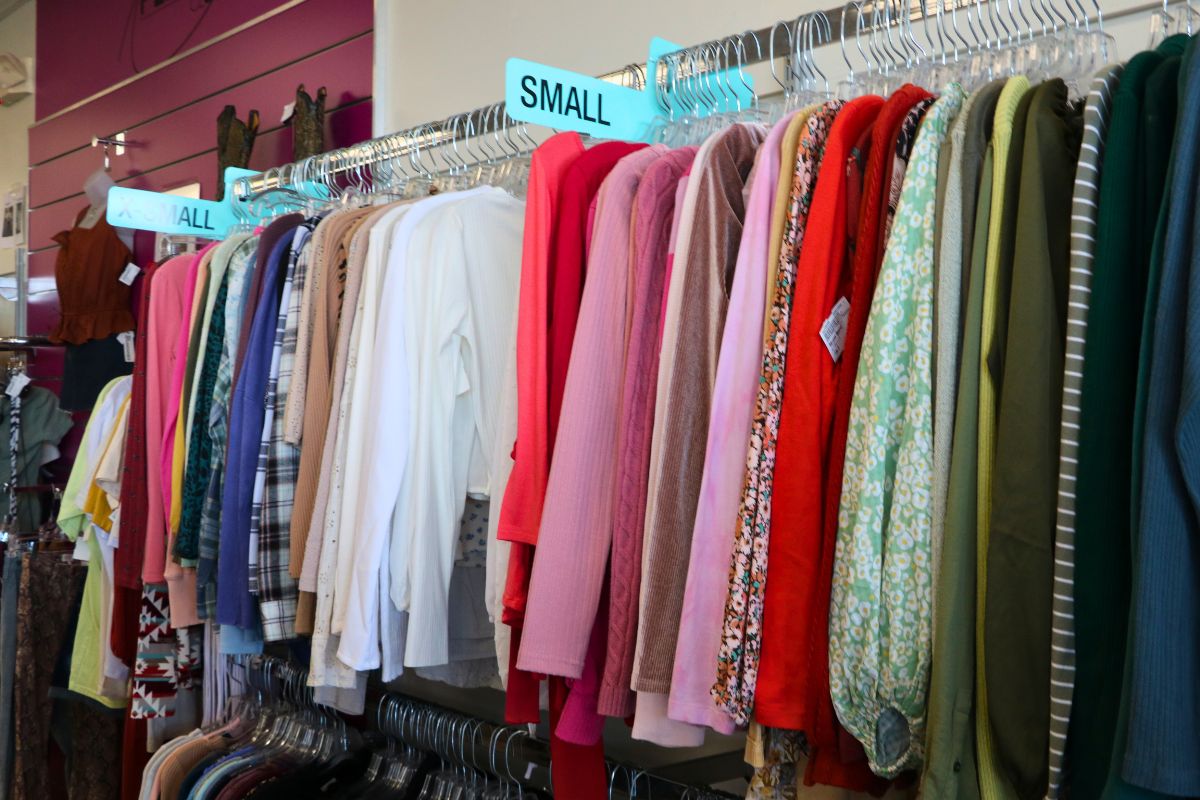 A rack of color-coordinated clothing from bright, red clothing to darker, green and blue clothing feature long, blue signs reading, "Small,' and, "X Small."