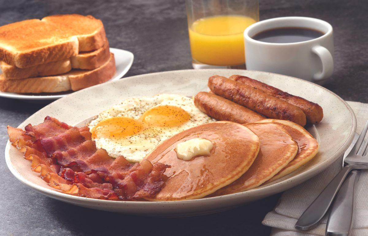 a breakfast platter featuring bacon, eggs, sausage and pancakes