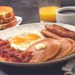 a breakfast platter featuring bacon, eggs, sausage and pancakes