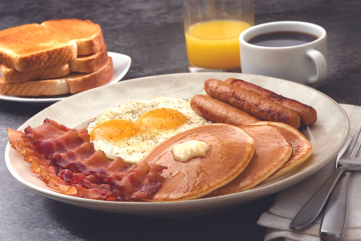 a breakfast platter featuring bacon, eggs, sausage and pancakes
