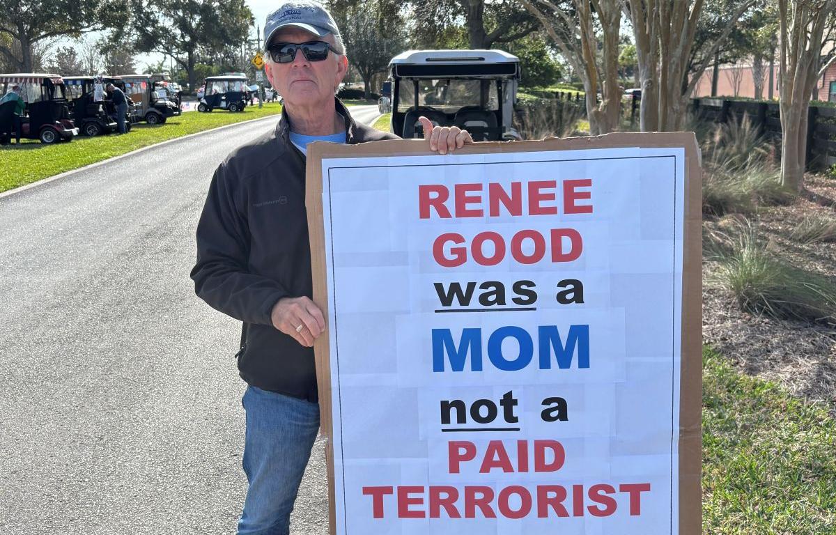 a man holds an anti-ICE sign at a protest in The Villages, Florida