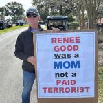 a man holds an anti-ICE sign at a protest in The Villages, Florida