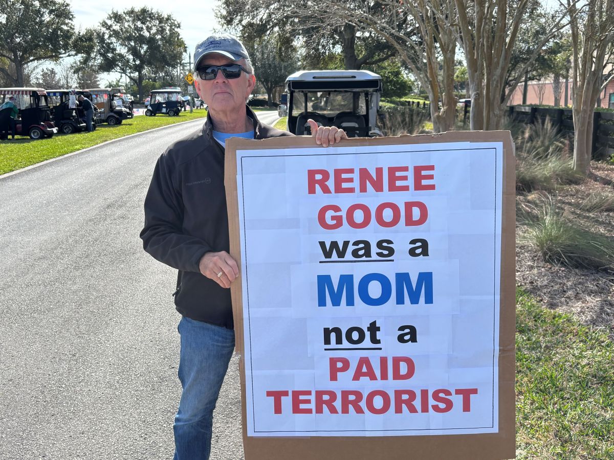 a man holds an anti-ICE sign at a protest in The Villages, Florida
