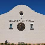 An old building features windows lining a wall with a large, City of Belleview logo in the center and letters above it reading, "Belleview City Hall."