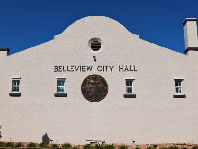 An old building features windows lining a wall with a large, City of Belleview logo in the center and letters above it reading, "Belleview City Hall."