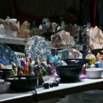 Two white tables feature a variety of crystals in different shapes and sizes on display with bowls featuring smaller ones.