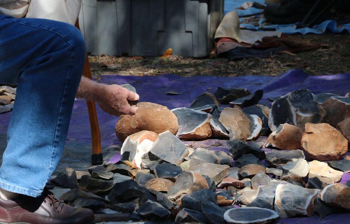A man kneels over broken rocks, examining them.