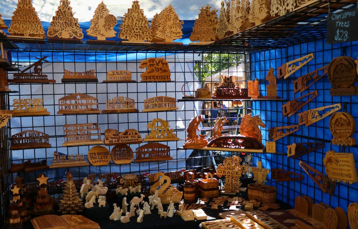 Wooden items in the shape of animals, words and scenery are displayed on shelves inside of a canopy.