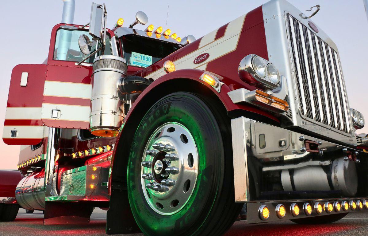 A large red truck with white stripes featured lights surrounding the bottom and top with green lighting illuminating the wheels and stairs from other trucks.