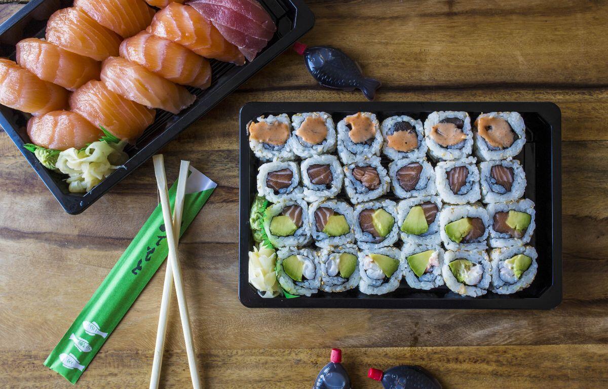 A plate of sushi with chopsticks on a wooden table.