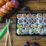A plate of sushi with chopsticks on a wooden table.