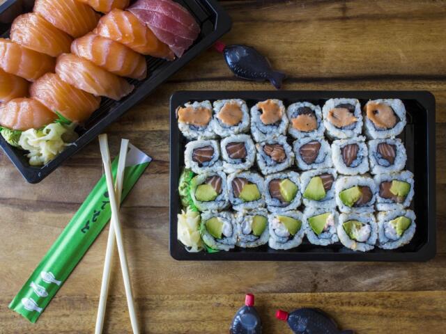 A plate of sushi with chopsticks on a wooden table.