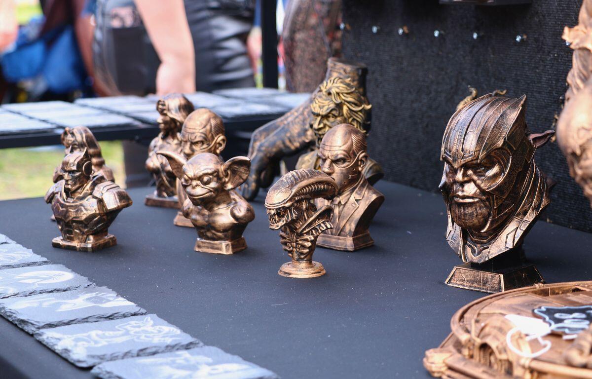 A table of bronze, 3D printed sculptures stands at a market.