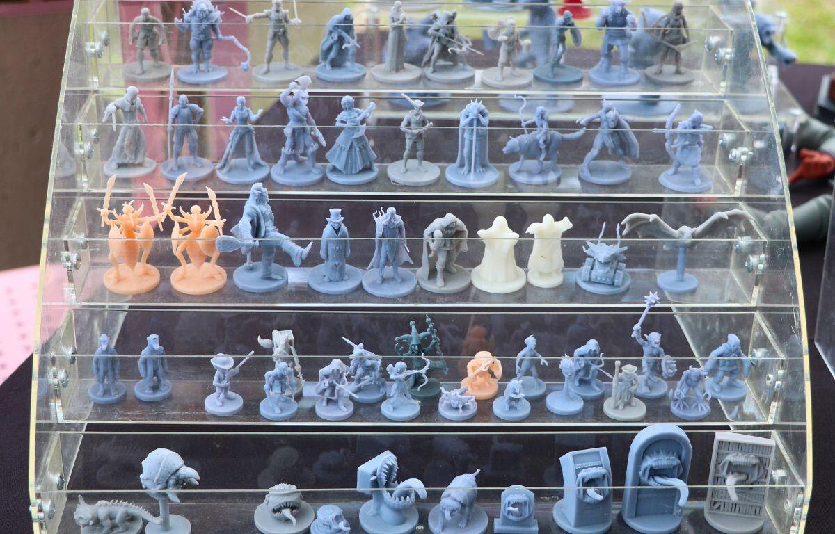 Multiple small figurines are lined up on a clear display shelf.