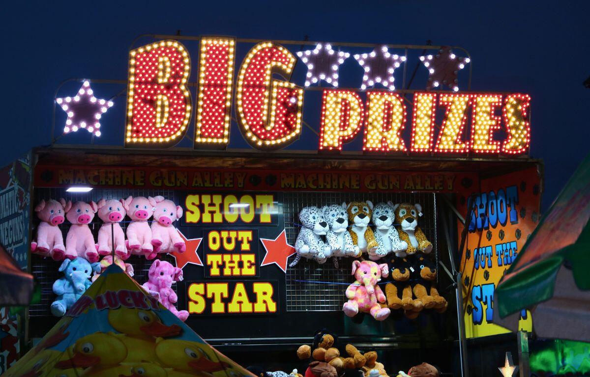 A large, light up sign reads, "Big Prizes." Underneath is a fair game with prizes hung on a wall.