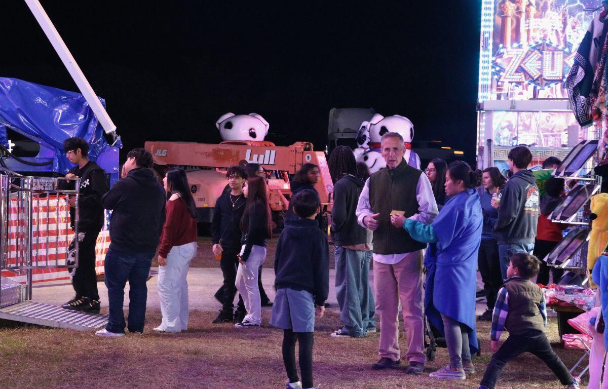 A group of people wait in line for a ride at a county fair.