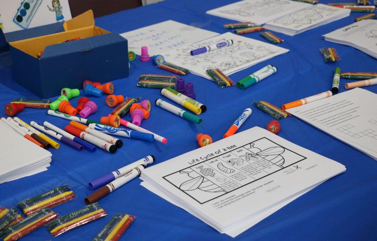 A table with kids' coloring pages features stamps, markers and crayons scattered around for children to play.