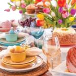 A colorful table display with tulips, roasted ham and colored cups and plates.