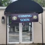 A beige storefront with a sign that reads, "Coming Soon."