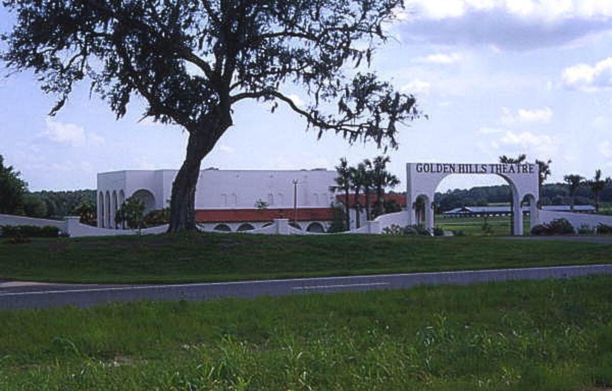 A colored photo of a white building labeled "Golden Hills Theatre" behind a tree.