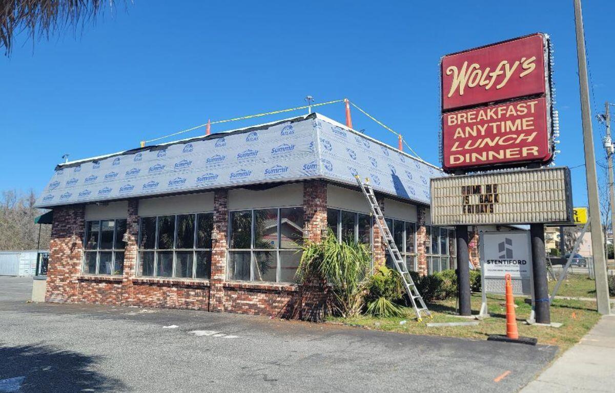 A colored photo of a restaurant building with a sign that reads, "Wolfy's."