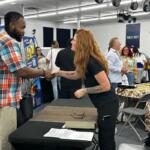 A job seeker shakes hands with a recruiter across a table at a hiring event.