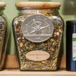 A closeup of glass jars of tea leaves sitting on a wooden shelf.