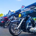 Motorcycles are lined up in front of a restaurant on a road. The restaurant features a sign above it reading, "Four Smokes BBQ."