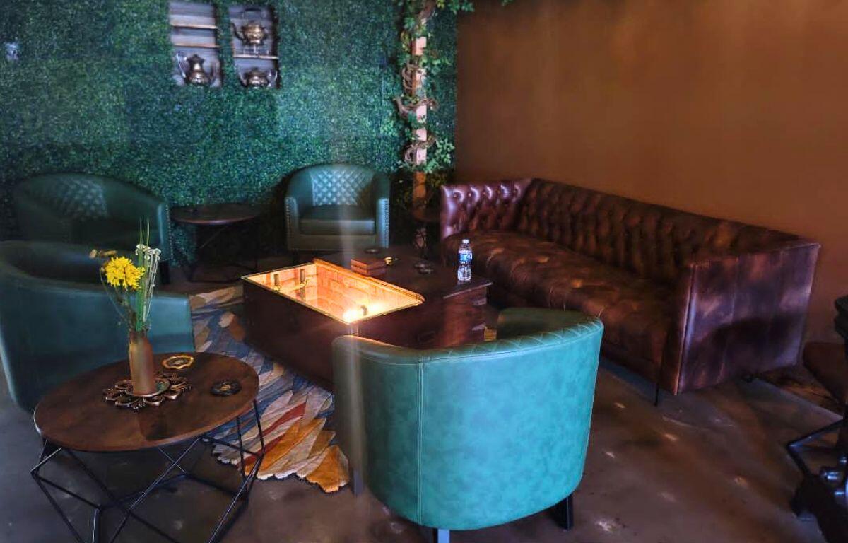 An indoor seating area is dimly lit with comfy couches and bright table.