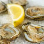 Five oysters laying on crushed ice, with a lemon garnished in the center.