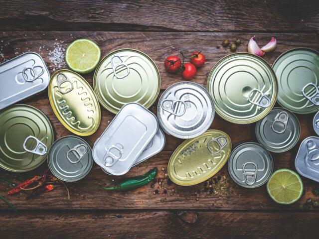 A colored image of canned goods top-down against a wooden background.