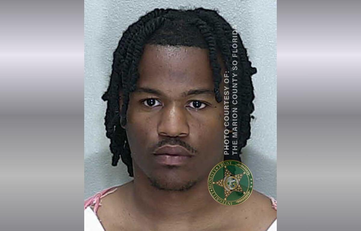 A colored image of an African American male with medium length hair in an orange and white striped jumpsuit,