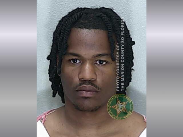 A colored image of an African American male with medium length hair in an orange and white striped jumpsuit,