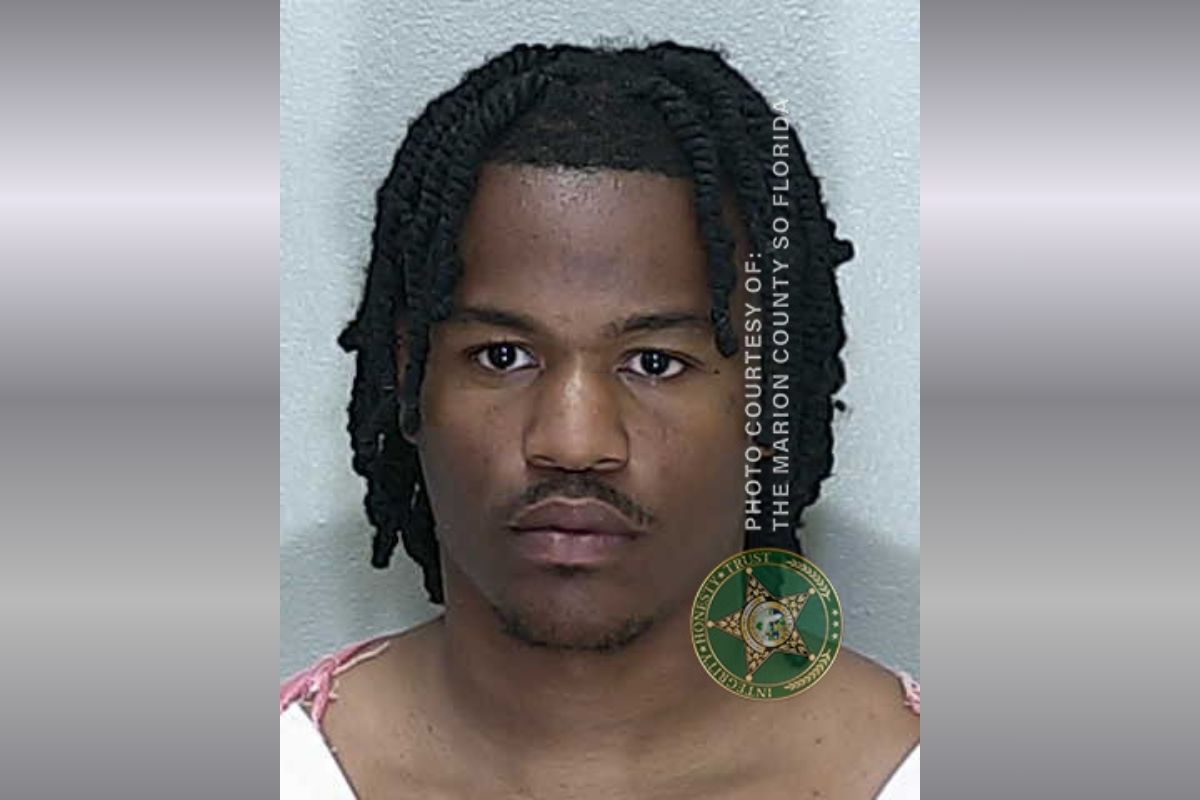 A colored image of an African American male with medium length hair in an orange and white striped jumpsuit,