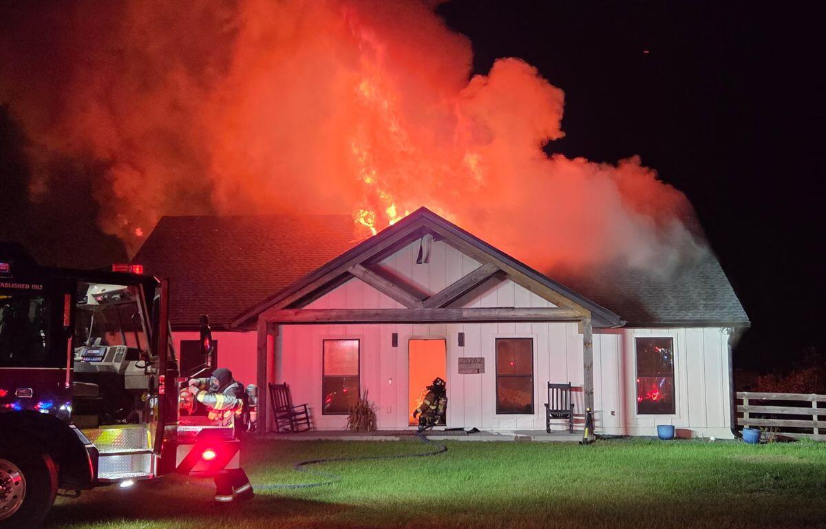 A colored photo of a home on fire, with a firetruck in front.