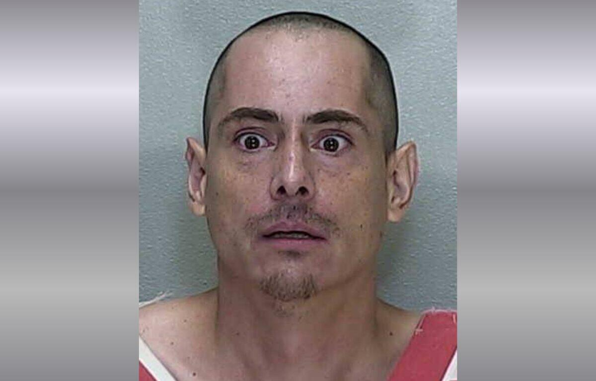 A mugshot of a man in a orange and white striped jumpsuit.