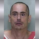 A mugshot of a man in a orange and white striped jumpsuit.