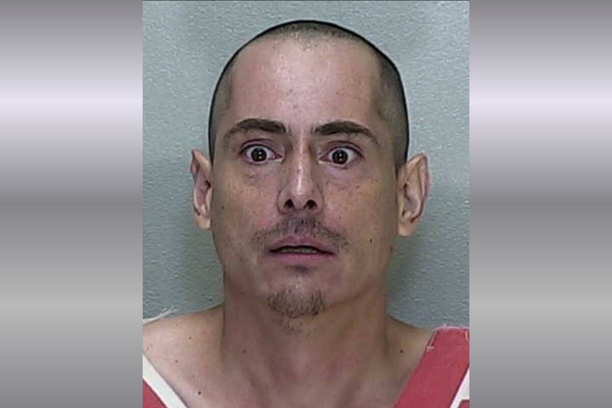 A mugshot of a man in a orange and white striped jumpsuit.