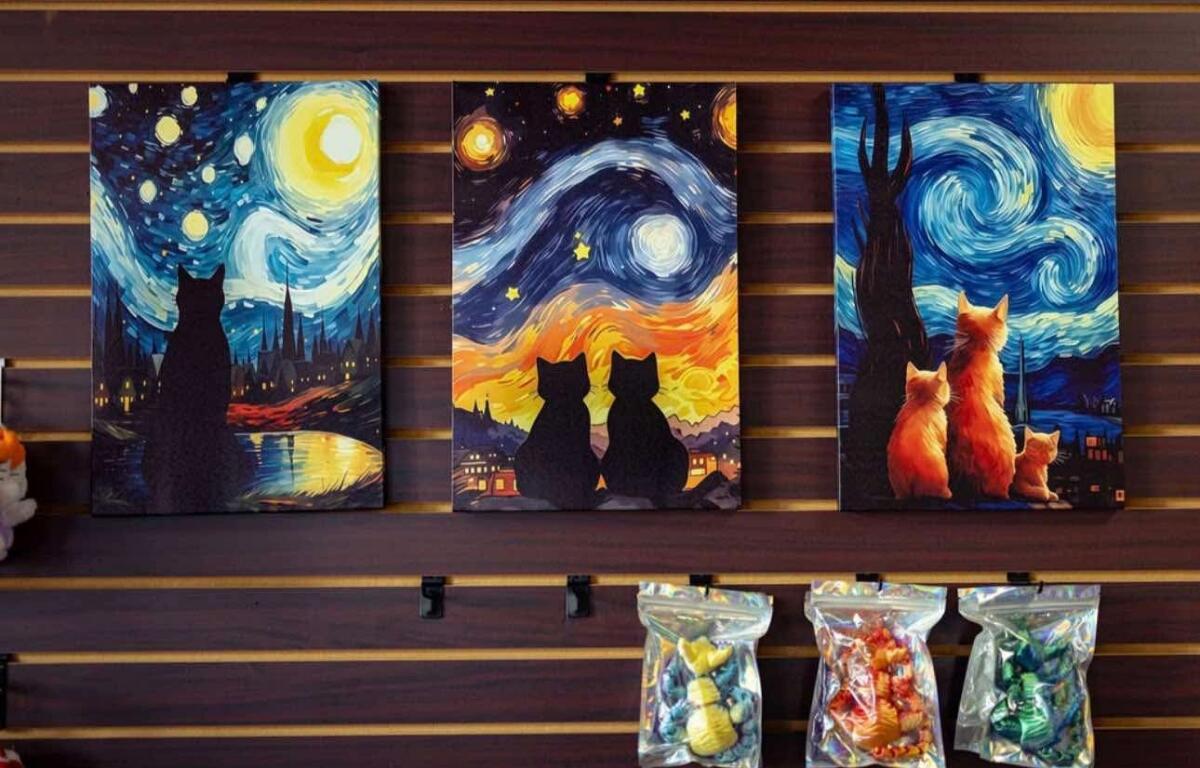 Three cat-themed canvas art panels on a wooden wall, showing starry skies and swirls of color.