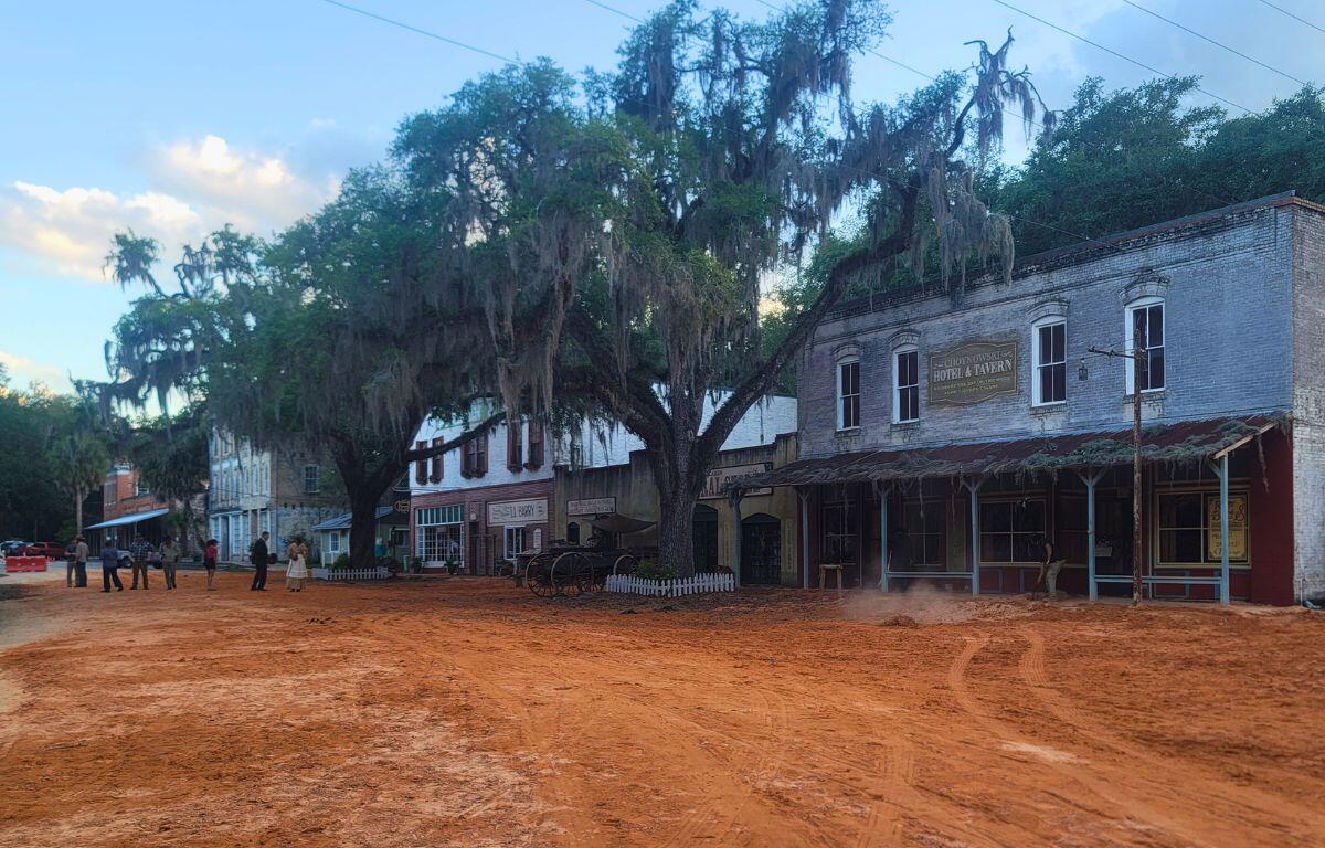 A town with a red, clay road features buildings set to look like the 1800s.