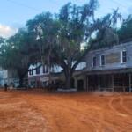 A town with a red, clay road features buildings set to look like the 1800s.