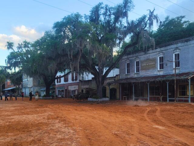 A town with a red, clay road features buildings set to look like the 1800s.