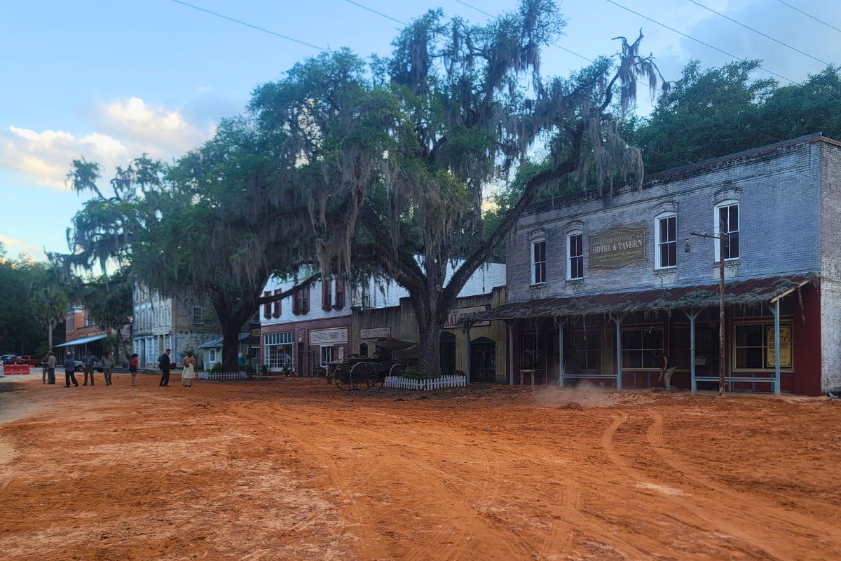 A town with a red, clay road features buildings set to look like the 1800s.