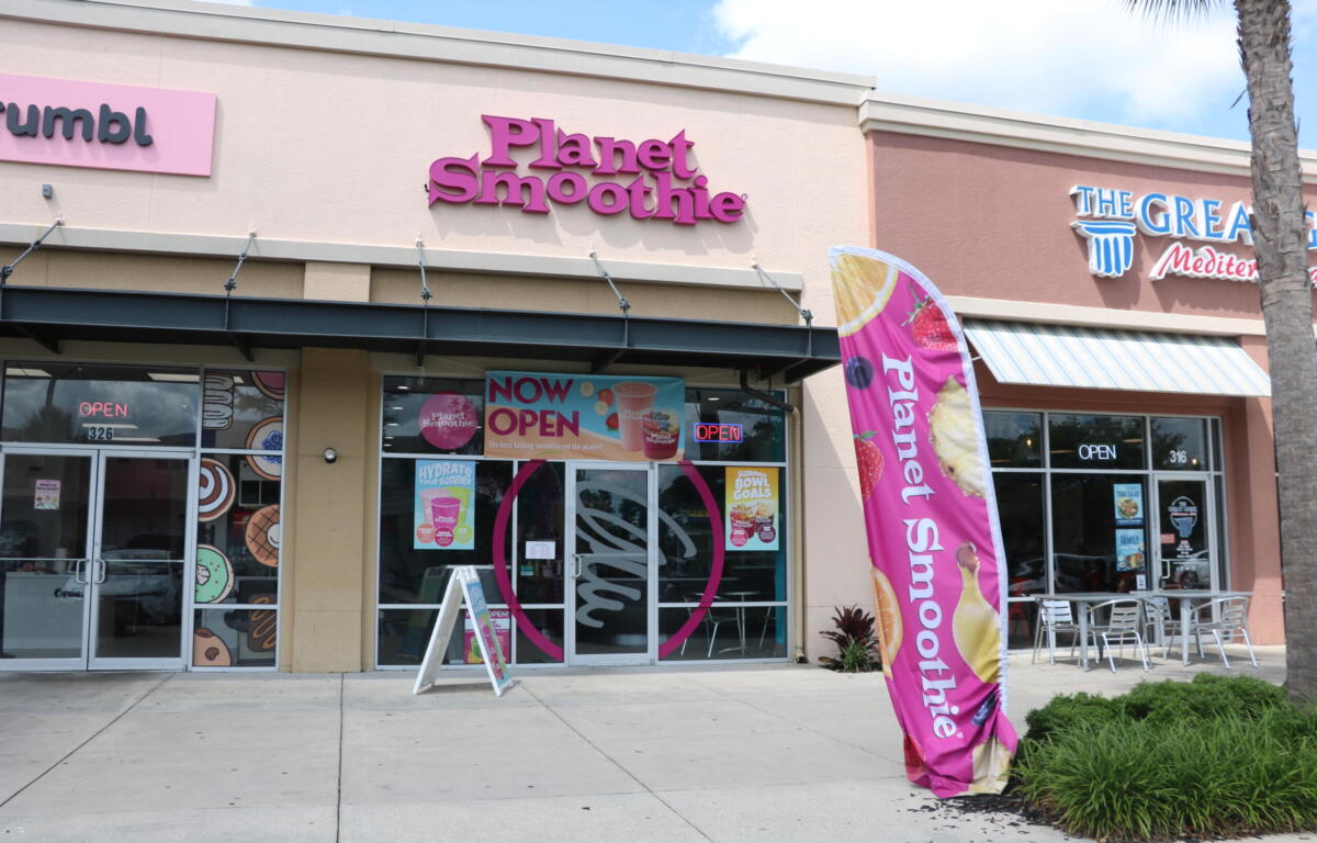 Exterior view of a shopping plaza. Three restaurants stand next to eachother, Crumbl, Planet Smoothie and The Great Mediterranean.