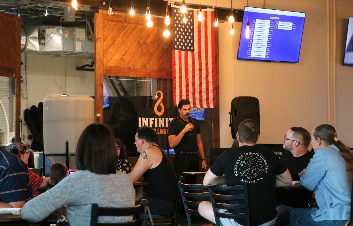 A crowd of guests in a restaurant watch as a man talks into a microphone.