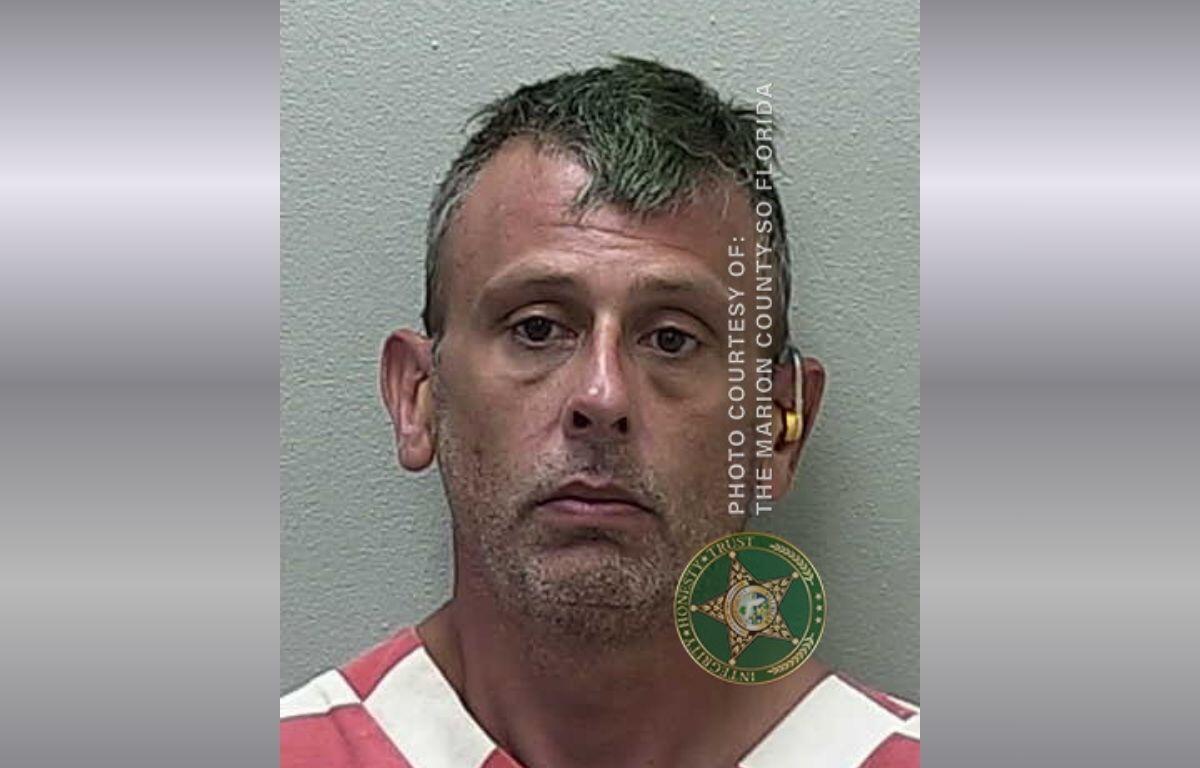 A mugshot of a man in an orange and white striped jumpsuit.
