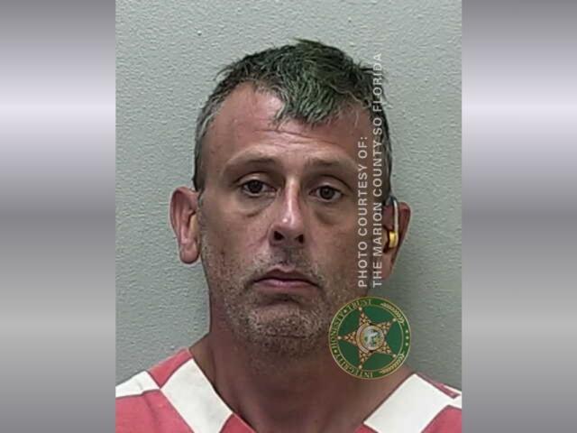 A mugshot of a man in an orange and white striped jumpsuit.