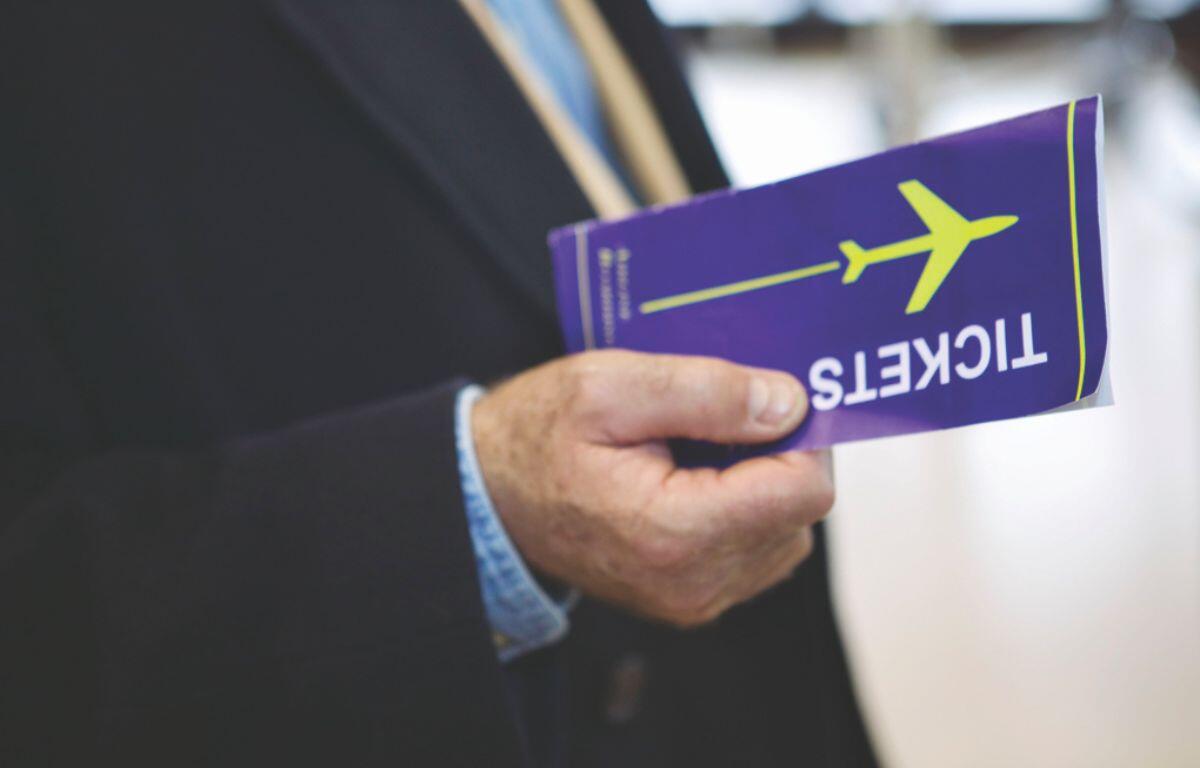 A colored image of a man in a suit holding a blue airline ticket.