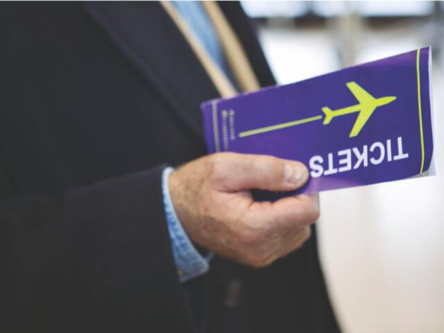 A colored image of a man in a suit holding a blue airline ticket.