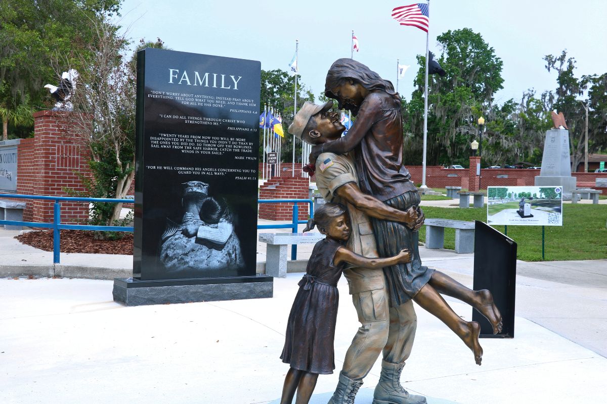 A statue of a soldier carrying his wife while a young girl hugs them from behind.